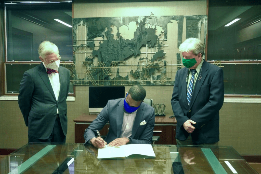 Image of Dr. James McClintock and Dr. Paul Erwing watching Mayor Woodlin sign a document.