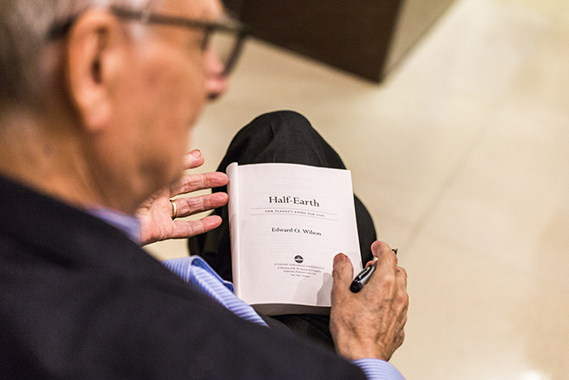 Image of E.O. Wilson holding a copy of his book Half-Earth. 