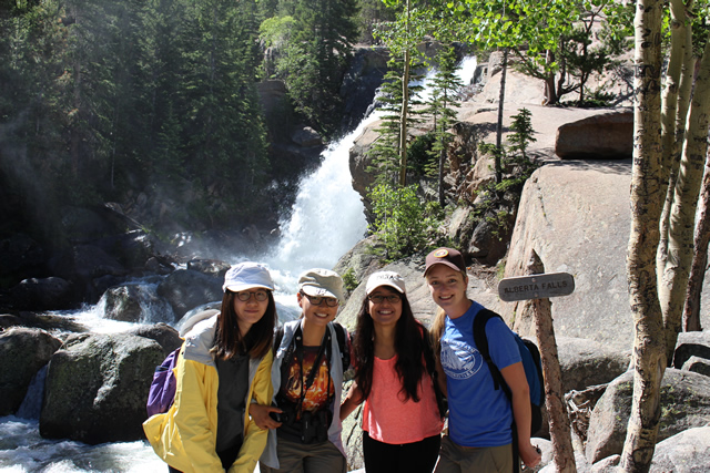 Image of four women standing in front of the waterfall. 