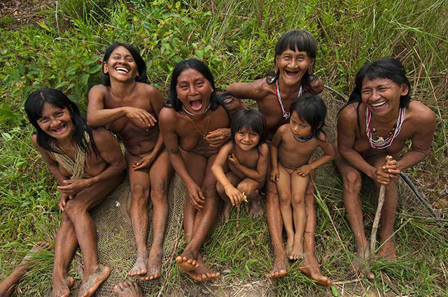 Laughing Hauorani women and children sitting in the forest in the Bameno Community Ecuador’s Yasuni National Park.