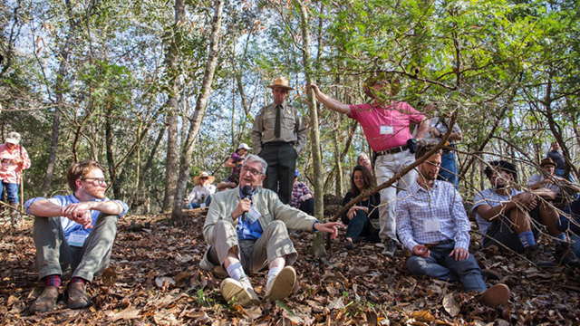 E.O. Wilson sitting in the forest with other people.