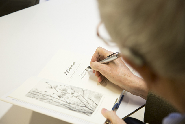 Image of E.O. Wilson signing a book. 