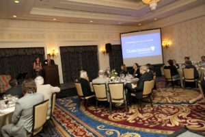 Image of people speaking onstage to a crowded room.