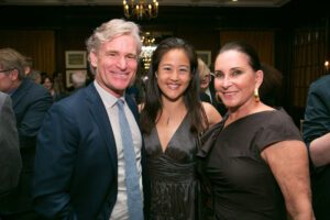 Image of three people smiling at the camera. 