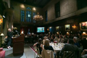 Image of Glenn Close giving a speech to a full dining room.