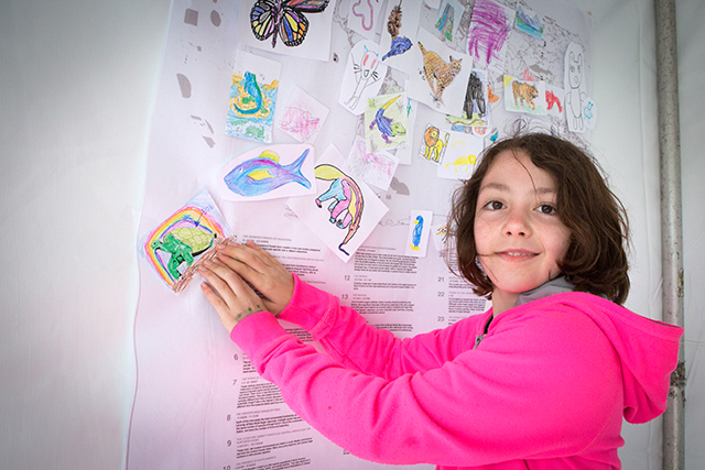 Image of a kid hanging up art.