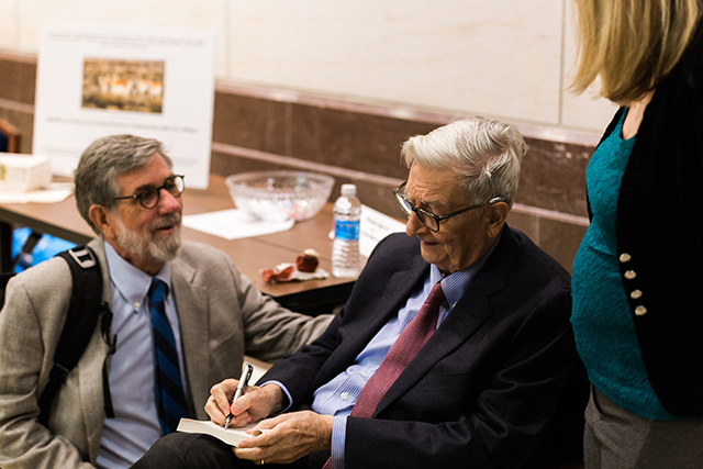 Image of E.O. Wilson singing a copy of his book.