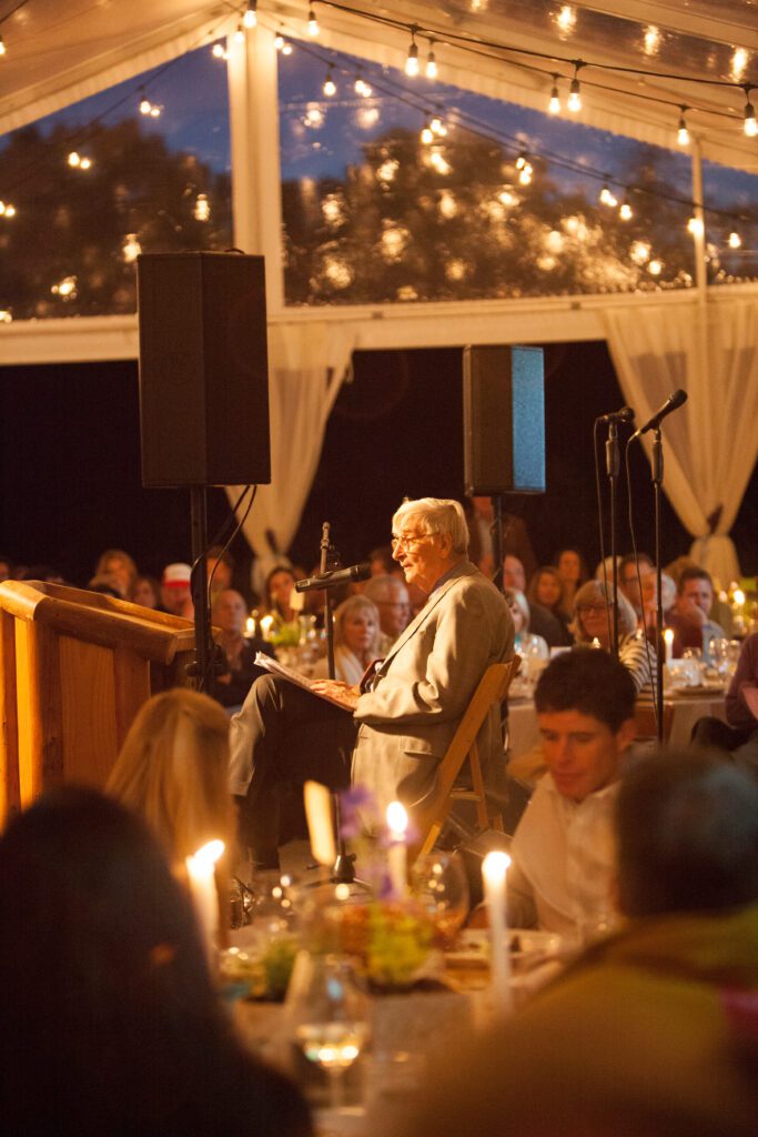 Image of E.O. Wilson sitting on stage addressing the audience. 