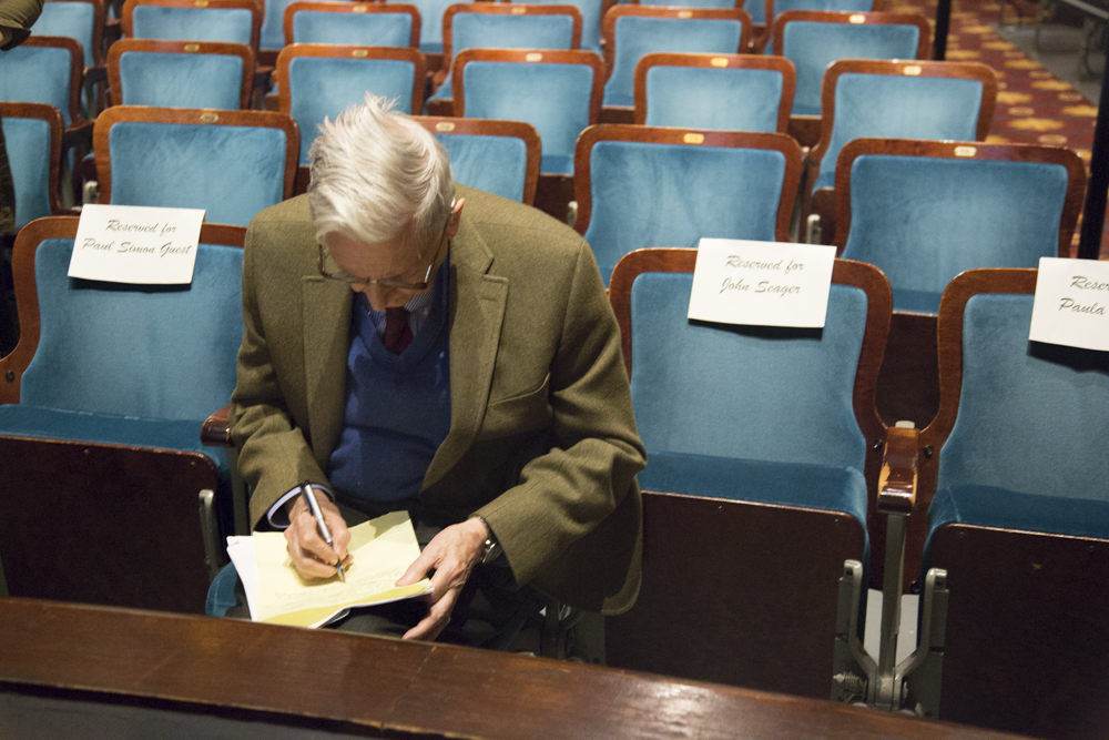 Image of E.O. Wilson sitting in a chair and writing on a piece of paper.