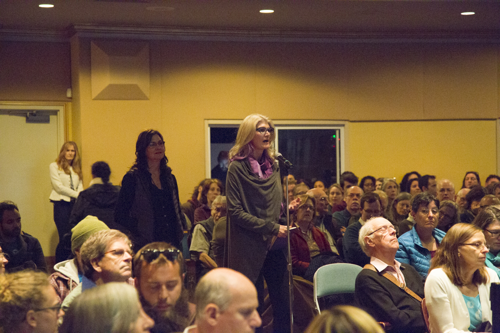 Image of people lined up to speak in a microphone.