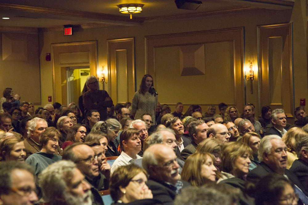 Image of people lined up to speak in a microphone.