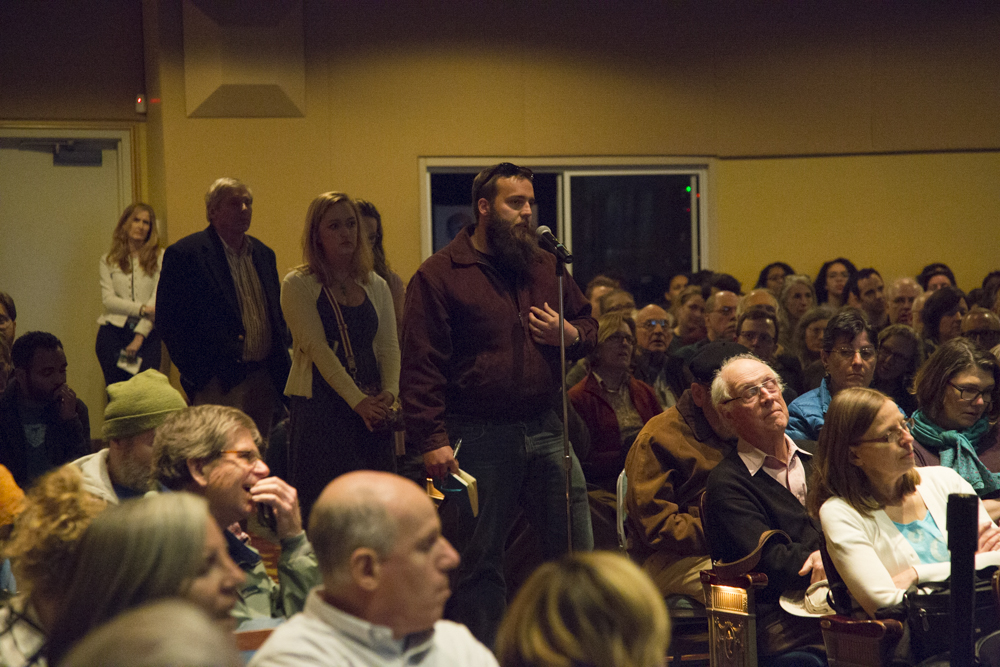 Image of people lined up to speak in a microphone.