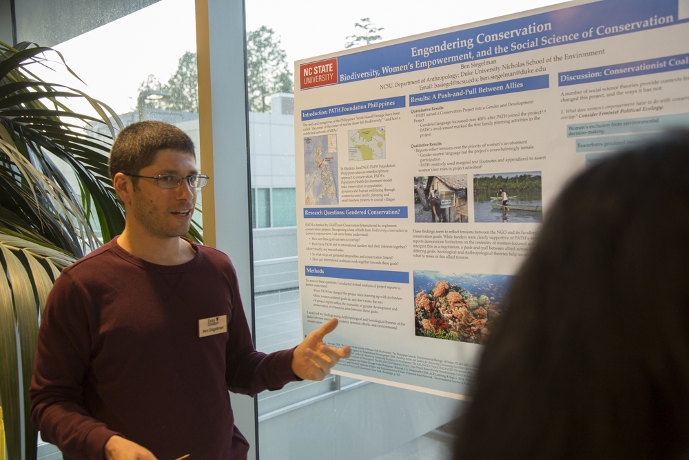 Image of a man standing in front of a poster.