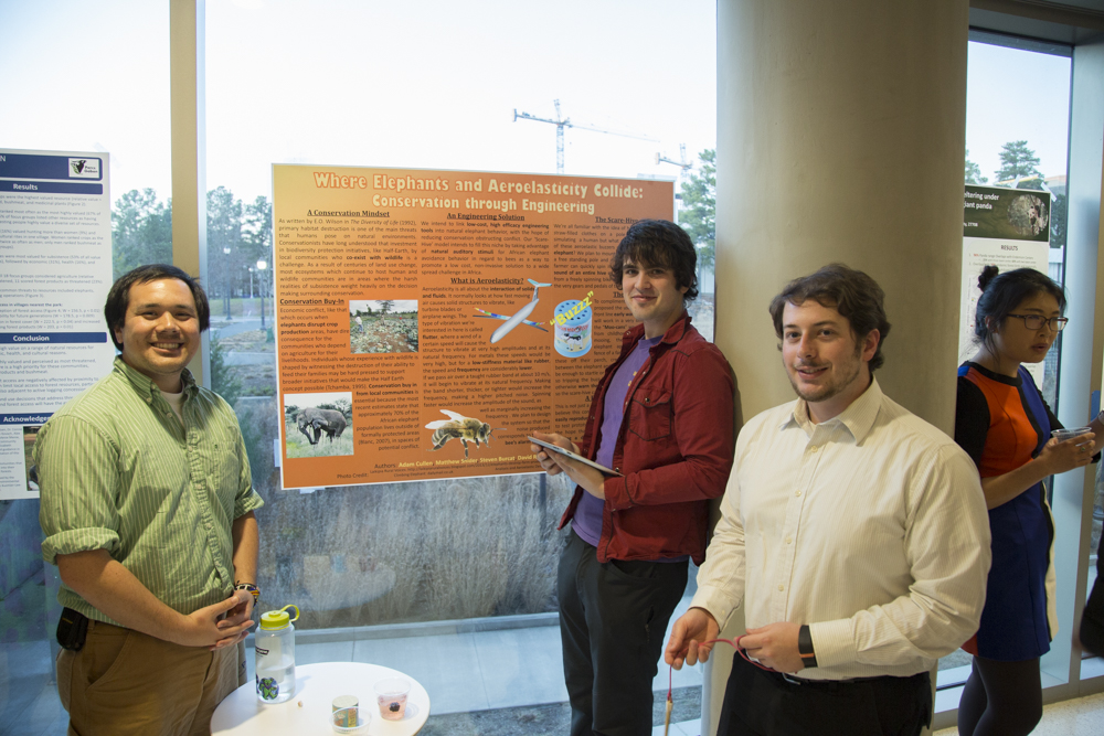 Image of a group of people standing in front of a poster.