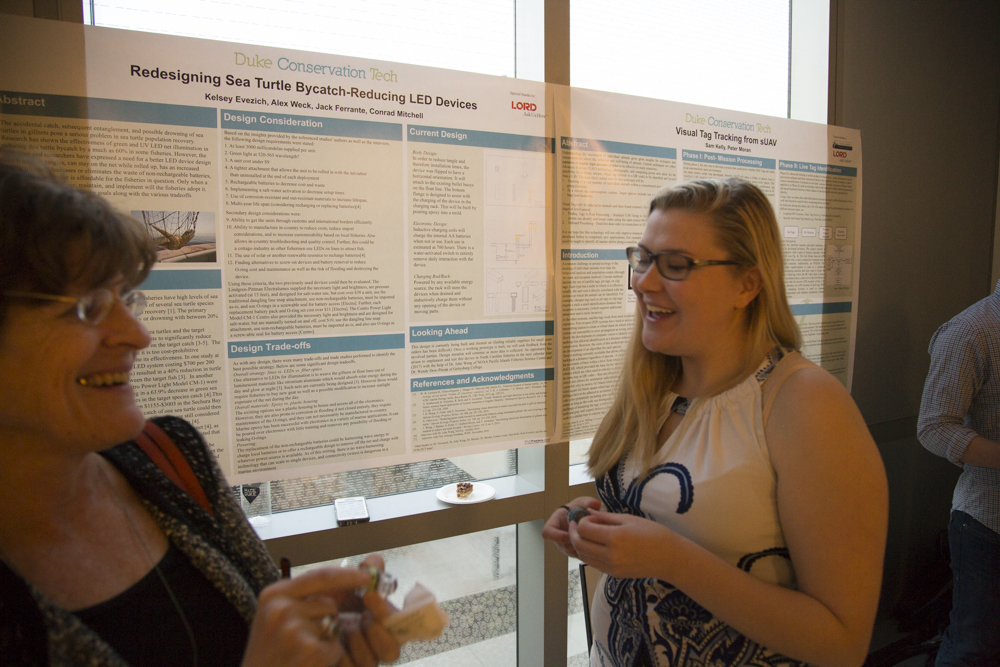 Image of a couple of women standing in front of a poster.