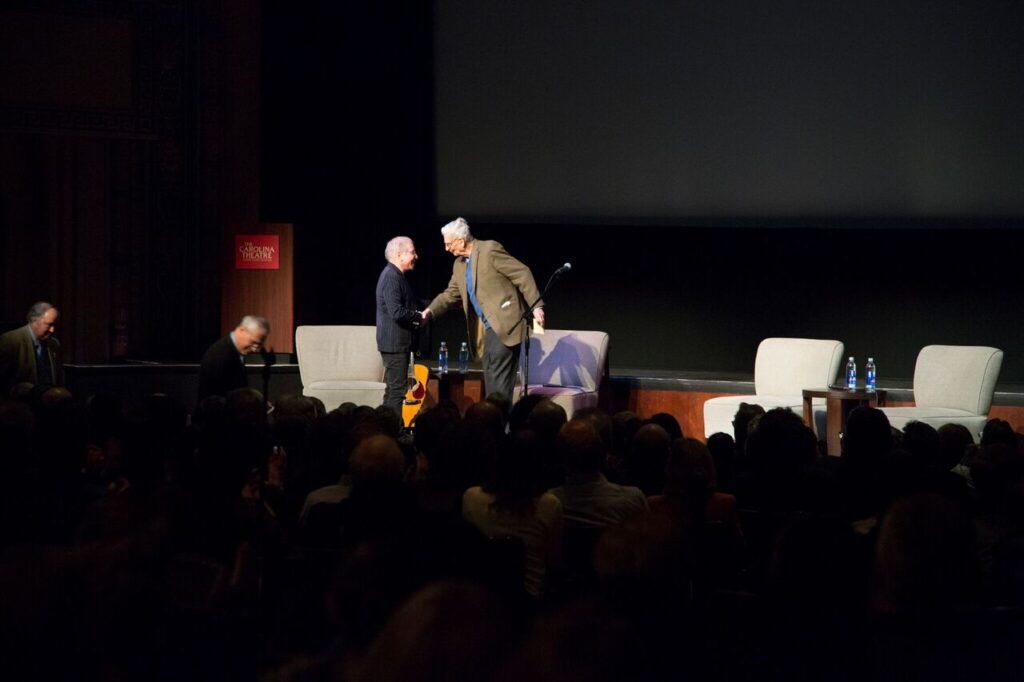 Image of E.O. Wilson shaking hands on stage with Paul Simmons.